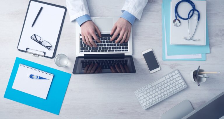 An office table with a notebook, cellphone and some medical devices