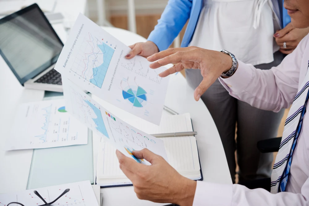 Two people looking at a sheet with graphs seem to analyze and discuss the information.