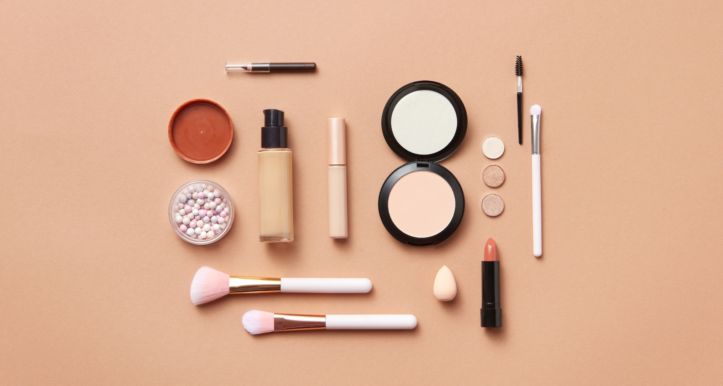 This image showcases a variety of cosmetic products and makeup accessories arranged on a pastel-colored background. The background create a soft, feminine aesthetic..