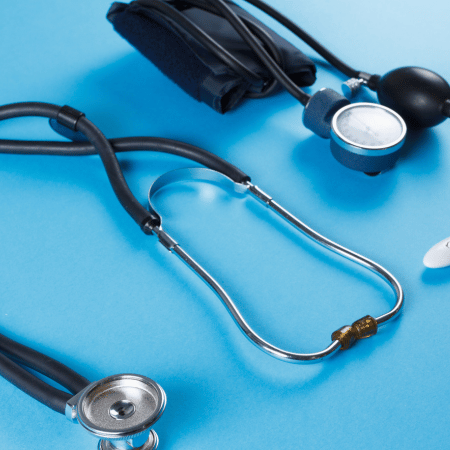 Stethoscope and pressure gauge resting on a blue background.