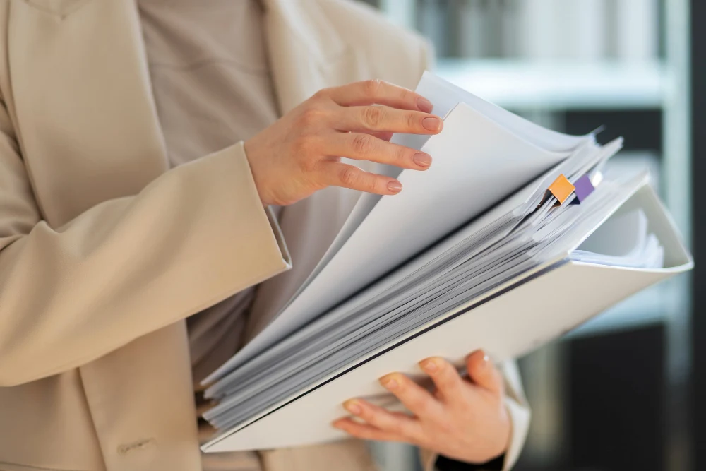 Female hands holding a folder with printed files, represents a technical file for medical device registration.